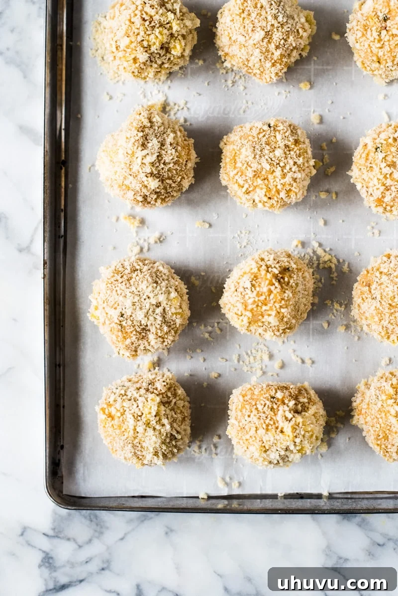 Zesty Fiesta Rice Bites 9 A baking sheet filled with raw Mexican arancini rice balls, ready to be baked to golden perfection.