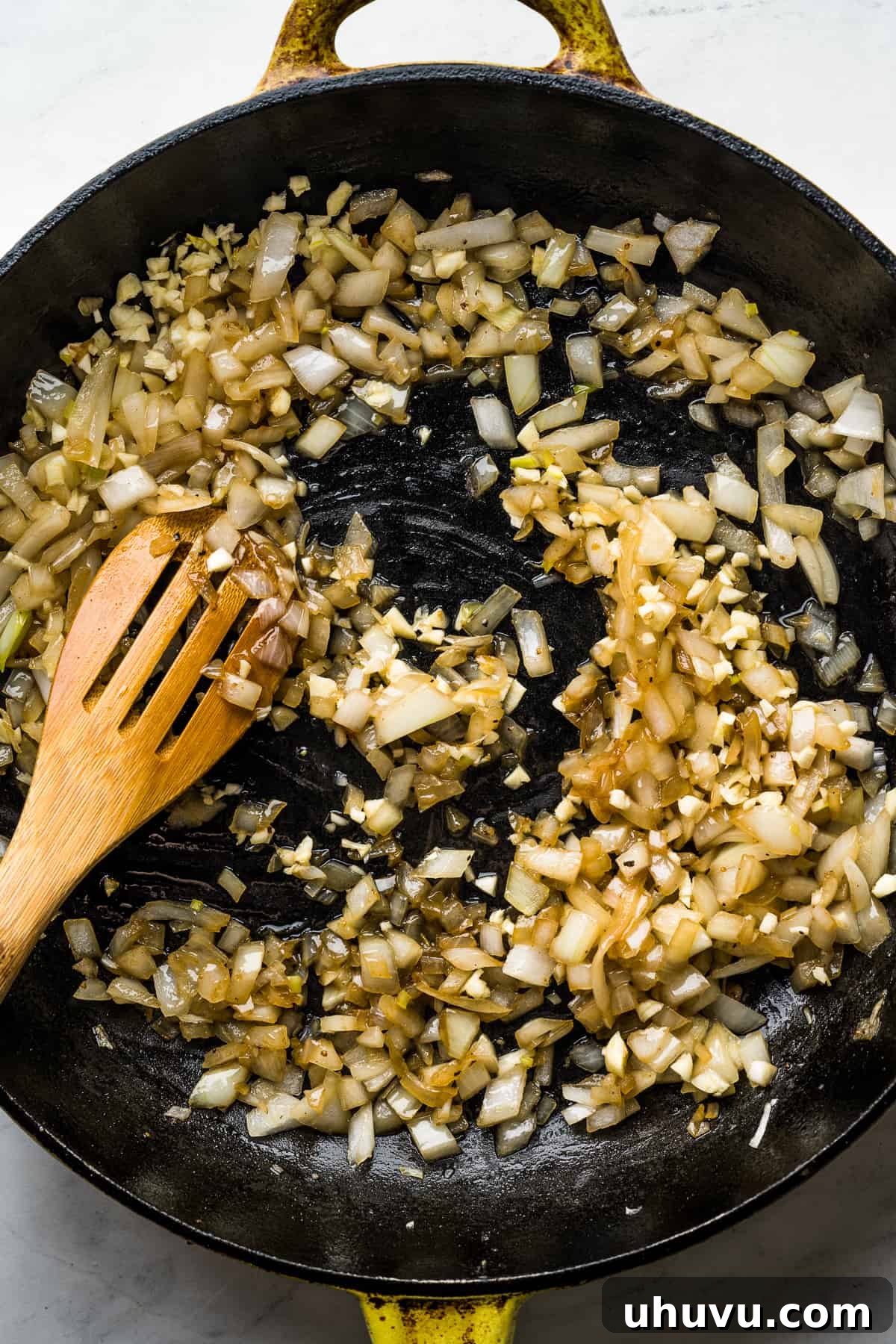 Melt-in-Your-Mouth Barbacoa 6 Diced onions being cooked with minced garlic in a large skillet, releasing their aromatic flavors.