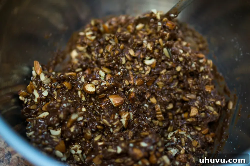 Chocolate mixture with chopped nuts being stirred in for no-bake chocolate bites.