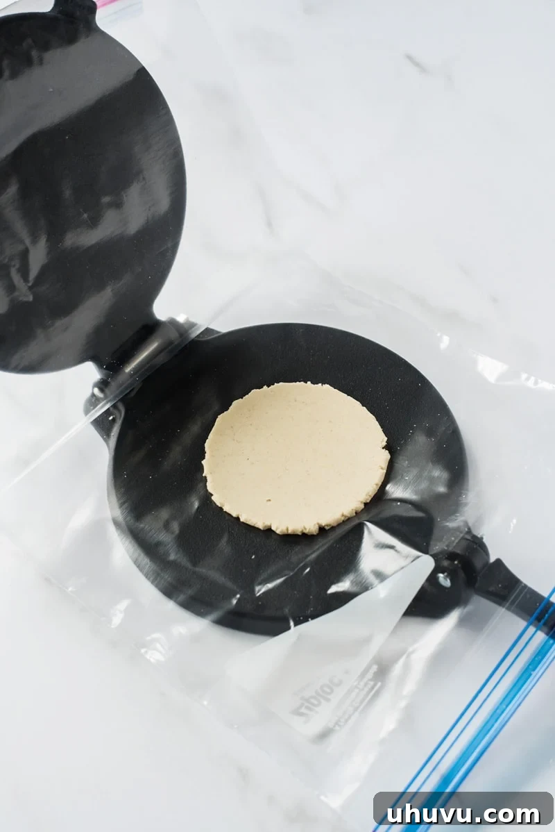 Homemade Gorditas: Authentic Mexican Stuffed Corn Cakes 7 Pressed raw corn tortilla on a black cast iron tortilla press.