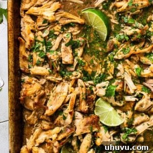 Chicken carnitas on a sheet pan with caramelized crispy edges and garnished with cilantro and fresh lime juice.