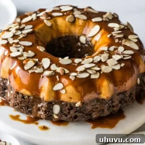 Chocoflan topped with cajeta and sliced almonds on a cake stand.