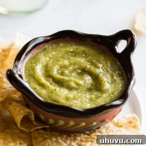 Salsa verde in a Mexican bowl next to some tortilla chips.