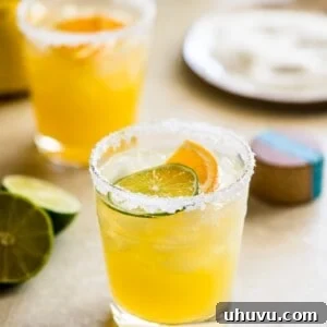 Skinny margarita cocktail glass garnished with sliced lime and orange.