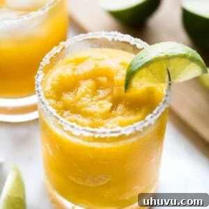 A mango margarita served frozen with a lime wedge.