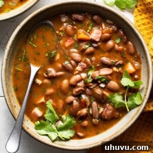 A bowl of charro beans topped with fresh cilantro on a table.