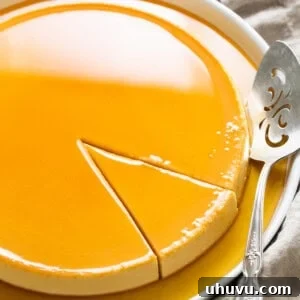 Flan de queso with caramel on top on a serving plate with a slice cut out ready to be served.