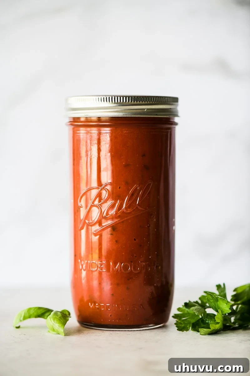 Quick Fiery Arrabbiata 2 Arrabiata sauce in a glass jar next to fresh basil and parsley.