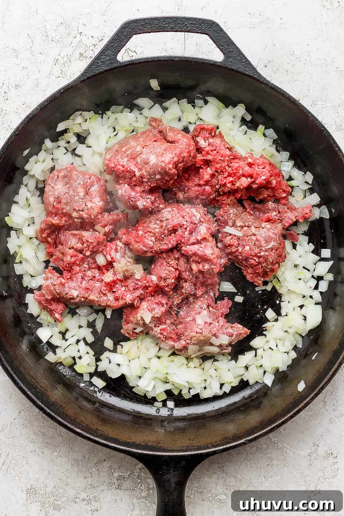 Classic Mexican Beef Hash 6 Ground beef and diced onions cooking in a large skillet, browning evenly.