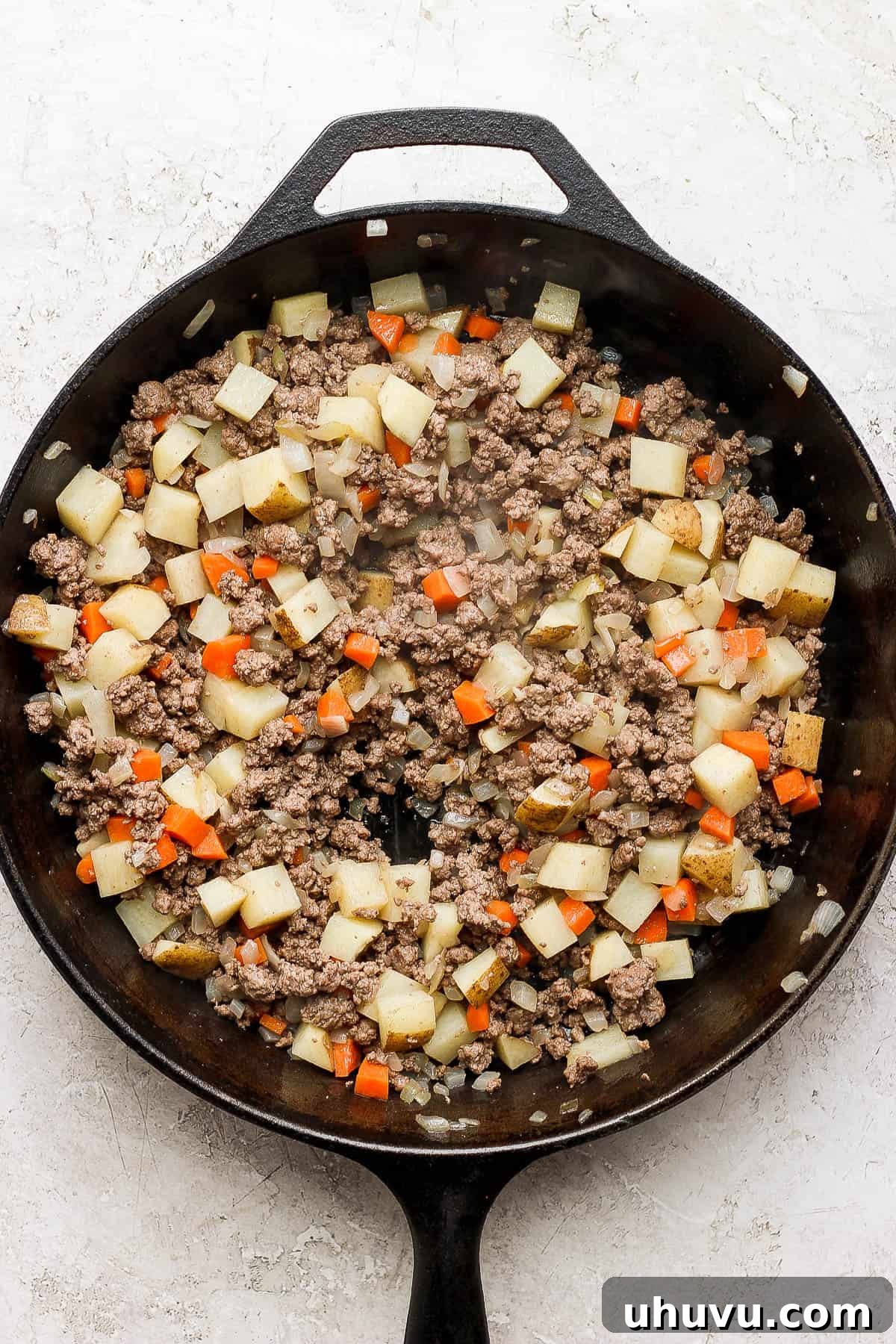 Classic Mexican Beef Hash 7 Ground beef, onions, diced potatoes, and diced carrots simmering in a skillet with the tomato sauce for picadillo.