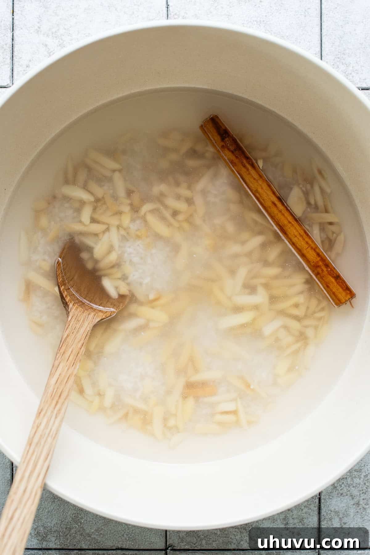 Rice, almonds, cinnamon, and water all soaking in a large bowl.
