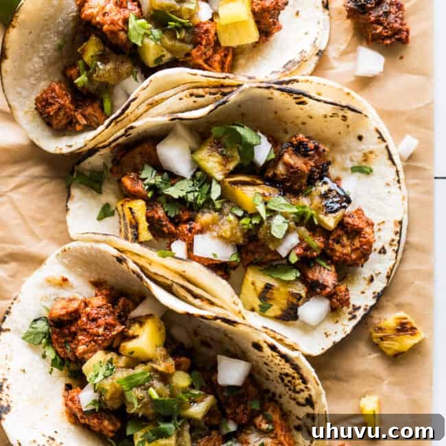 Tacos al pastor topped with grilled pineapple, cilantro, and white onion.