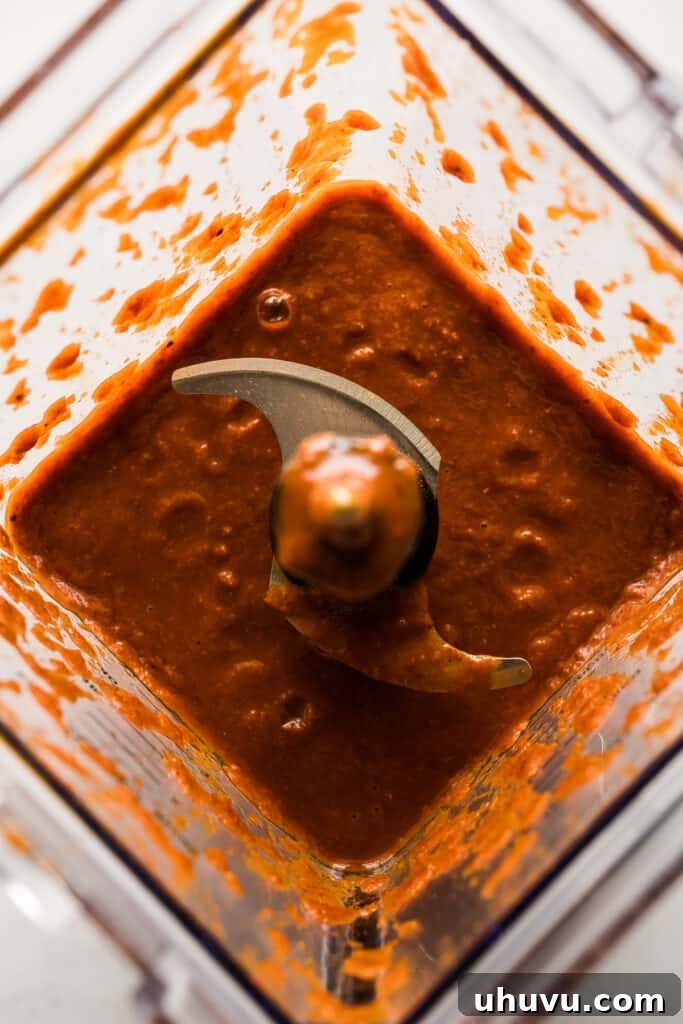 Tacos al pastor marinade blending to a smooth, vibrant red paste in a blender.