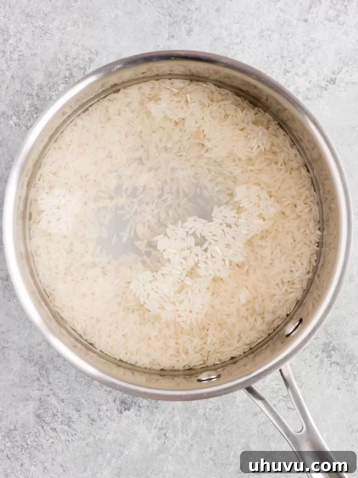 Uncooked rice and water in a saucepan on the stove, ready to be boiled.