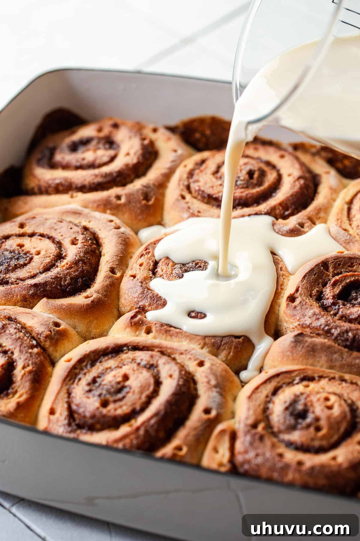 Tres Leches Drenched Cinnamon Buns 7 The luscious three-milk mixture being slowly poured over the warm, freshly baked cinnamon rolls.