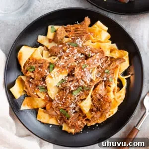 tender beef ragu served with pappardelle pasta on a black plate