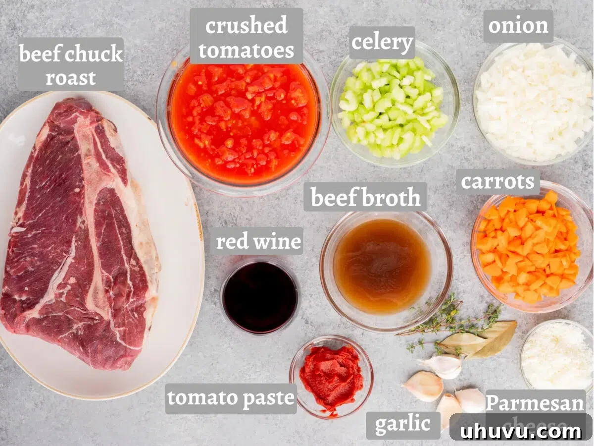Ingredients for Slow Cooker Beef Ragu including beef chuck roast, crushed tomatoes, onion, celery, carrots, garlic, tomato paste, red wine, beef broth, thyme, bay leaves, and Parmesan cheese.