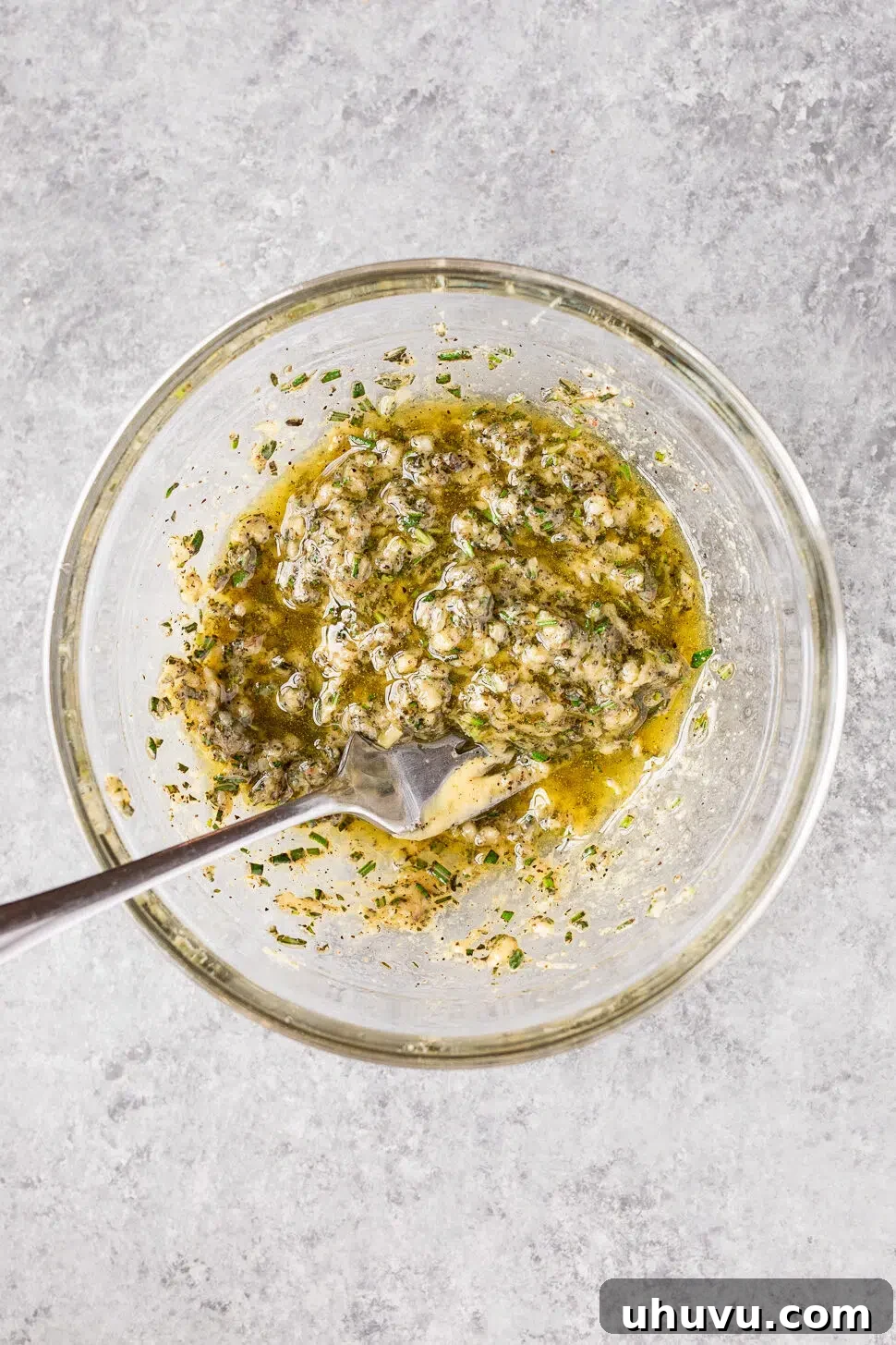 Garlic, rosemary, thyme, olive oil, and Dijon mustard mixed together to make the herb rub for roasted leg of lamb.