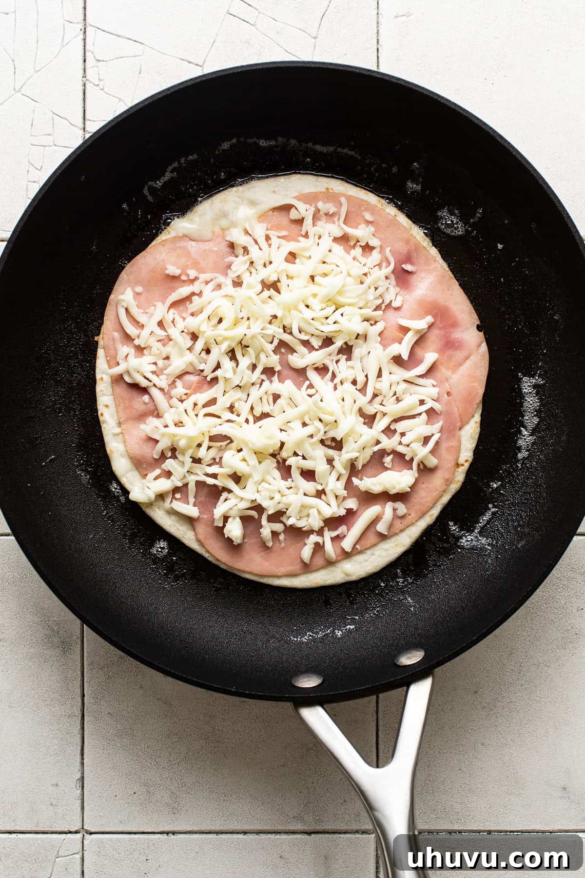 In Sync 5 Sliced ham and shredded Mexican cheese on a flour tortilla on a skillet.
