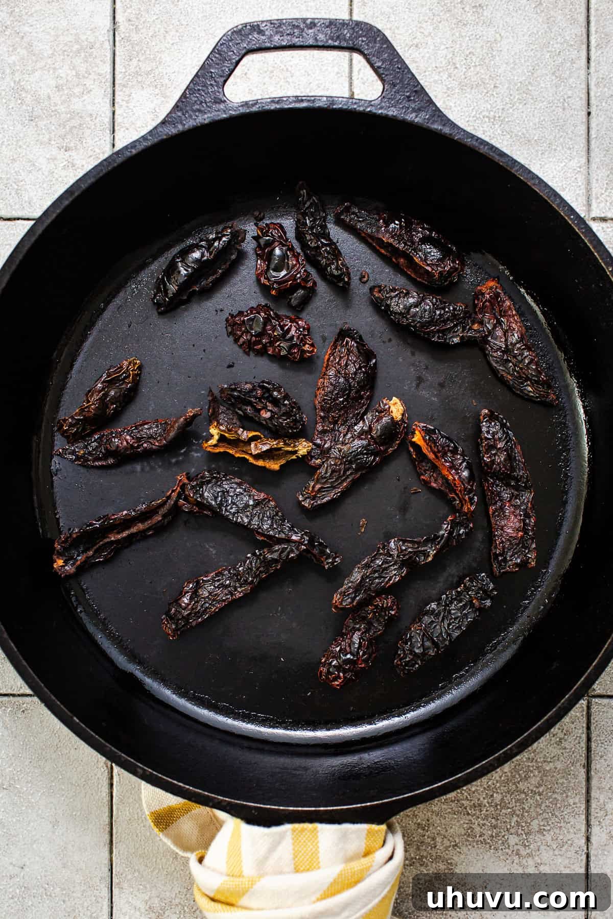 Dried chile moritas being toasted in a dry skillet to enhance their smoky aroma.