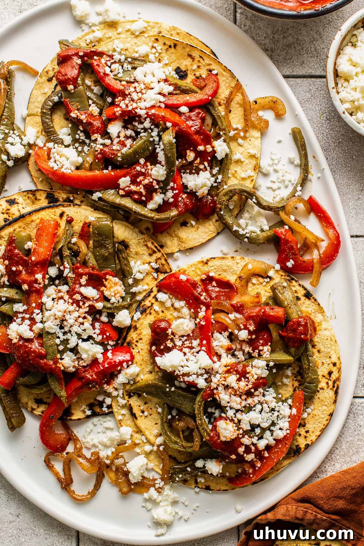 Charred Nopales Tacos with Fresh Salsa and Lime 8 Three nopales tacos on a plate topped with guajillo salsa and cotija cheese.