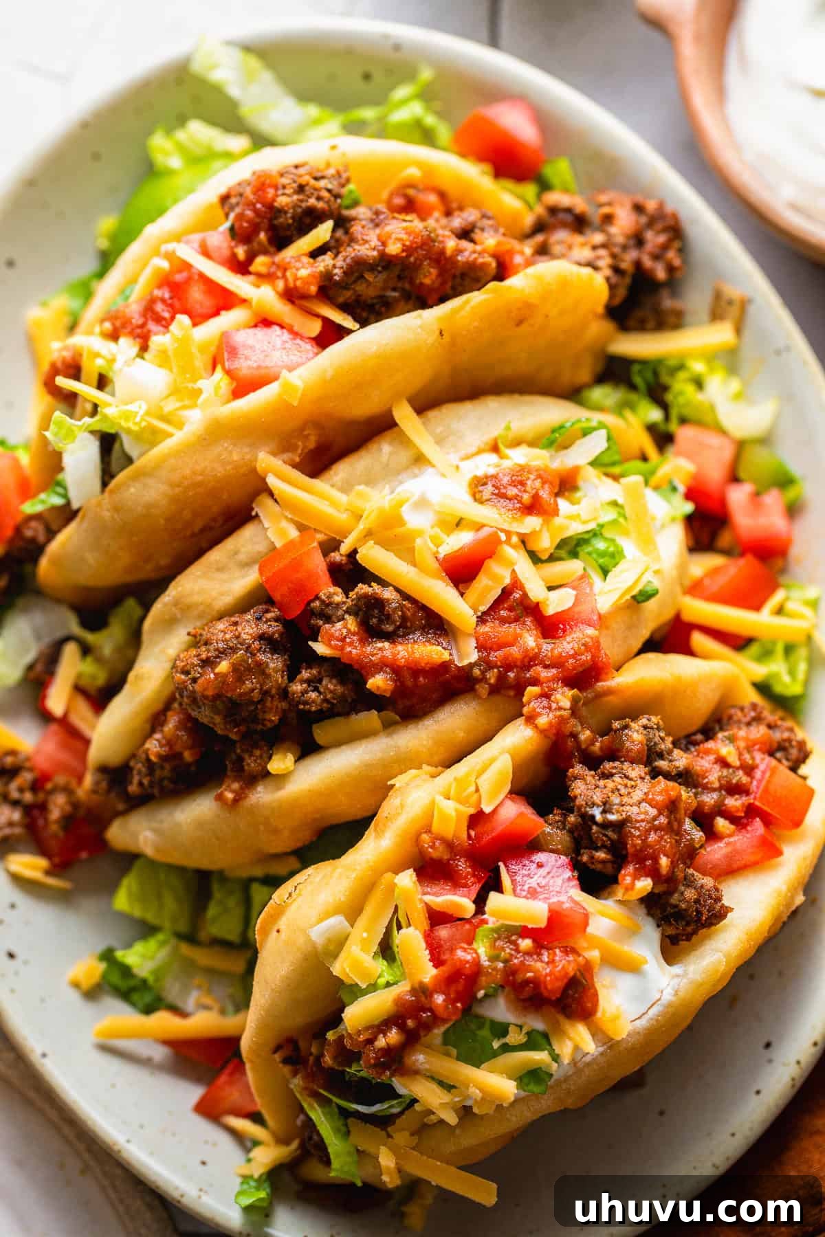 Crispy Homemade Chalupas Recipe 2 Assembled chalupas topped with ground beef, cheese, lettuce, tomatoes, and sour cream.