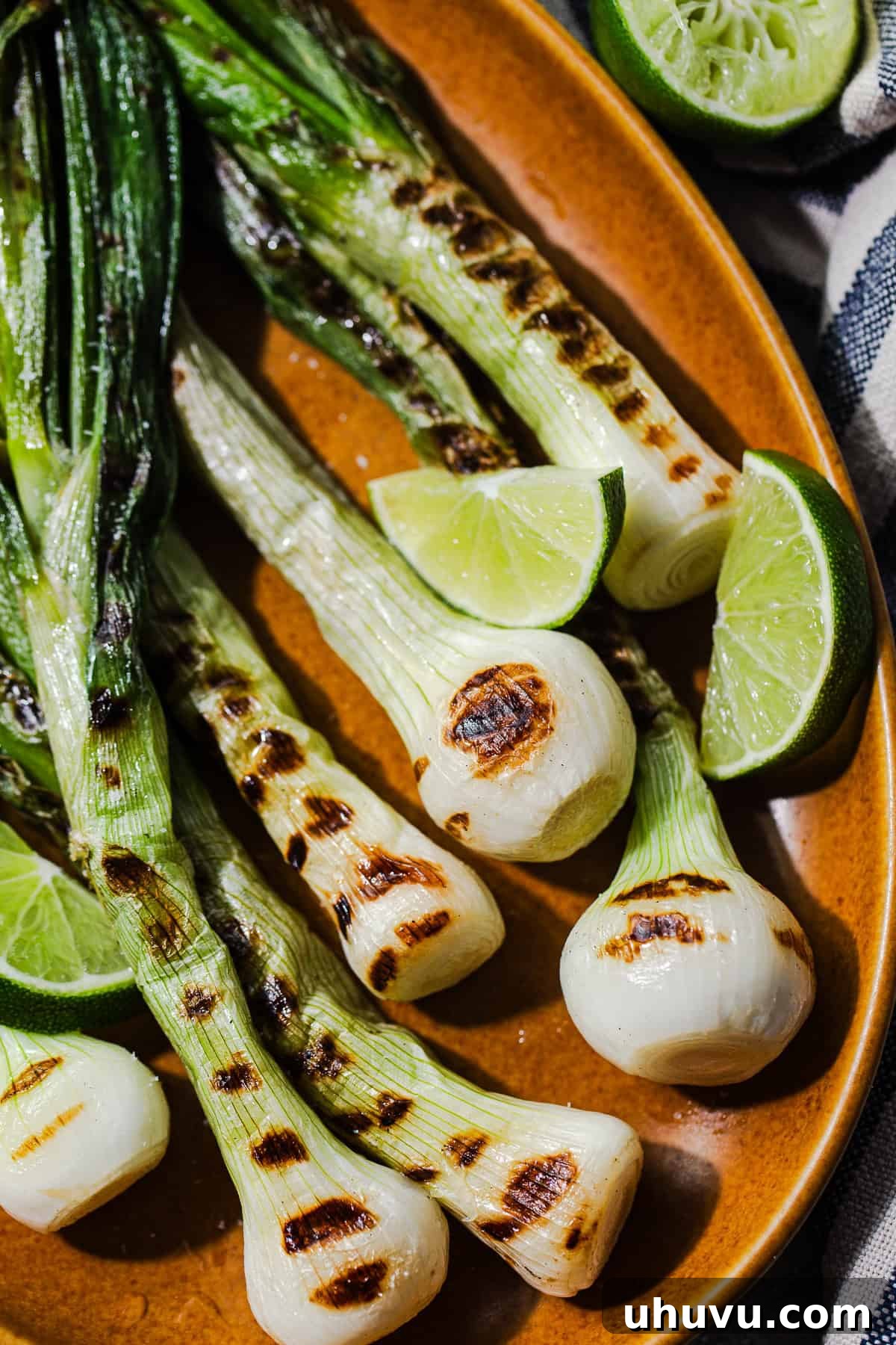 Grilled Cambray Onions Recipe (Cebollitas Asadas) 7 Close up of grilled cebollitas cambray with lime wedges ready to eat.