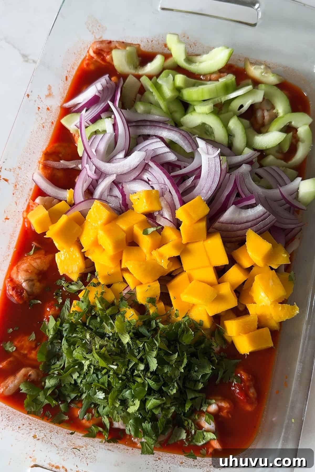 Red Aguachile with Shrimp and Fresh Lime 7 Cucumber, red onion, mango, and cilantro on top of a dish full of aguachile rojo before being mixed in.