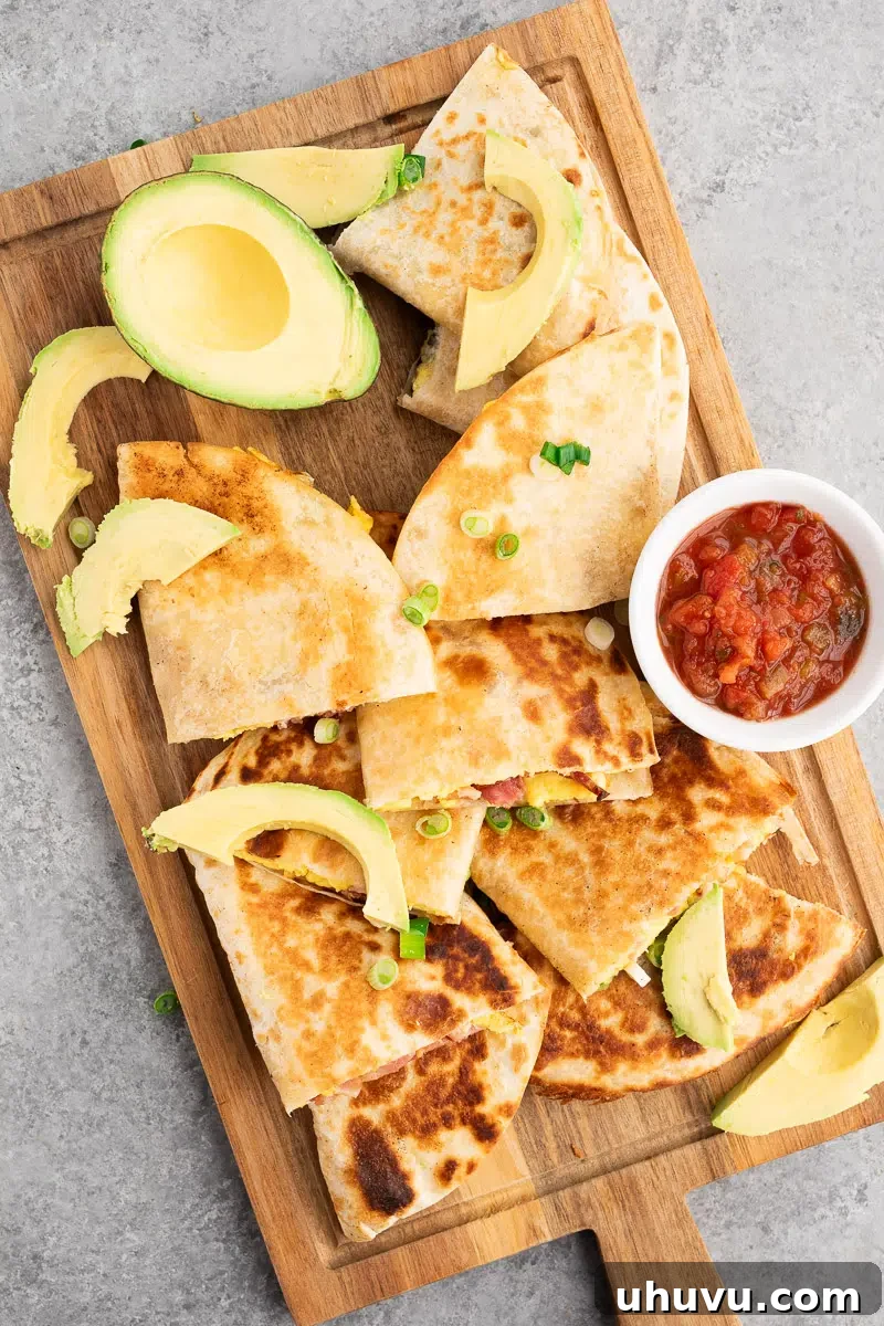 Cheesy Breakfast Quesadillas with Eggs and Salsa 7 sliced bacon and egg breakfast quesadillas on a cutting board