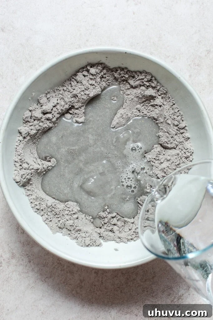 Authentic Blue Corn Tortillas Recipe 5 Water being poured into a bowl of blue corn masa for making blue corn tortillas.
