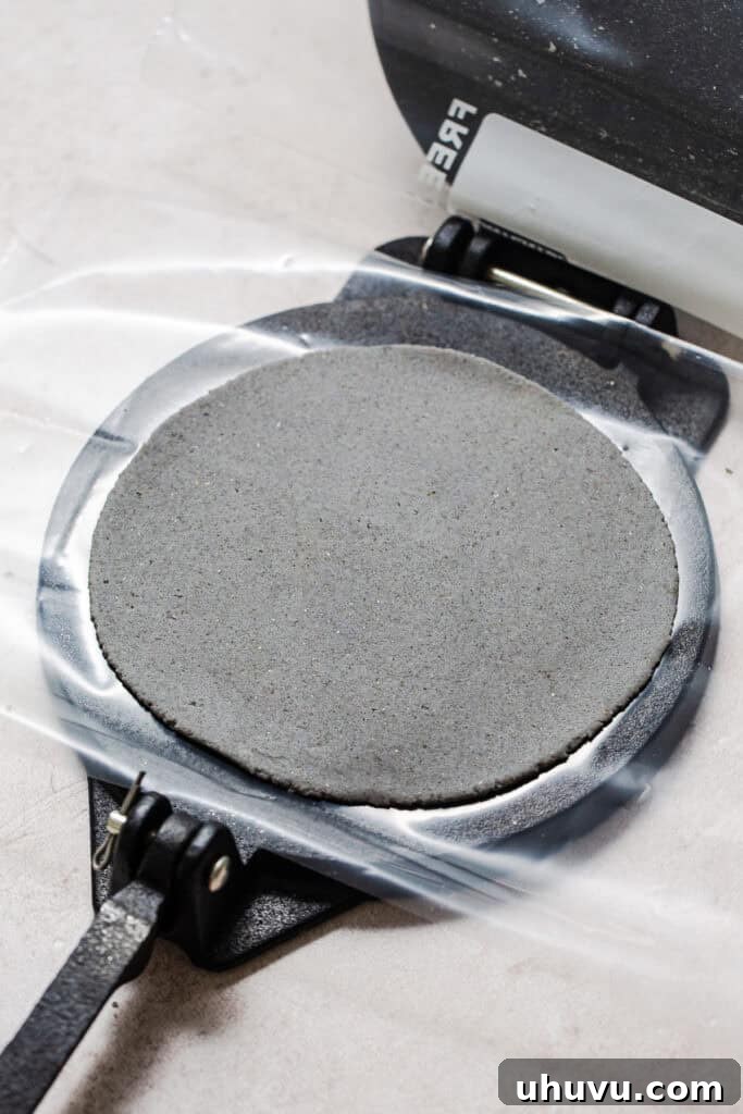 Authentic Blue Corn Tortillas Recipe 7 A blue corn tortilla pressed flat on a tortilla press.