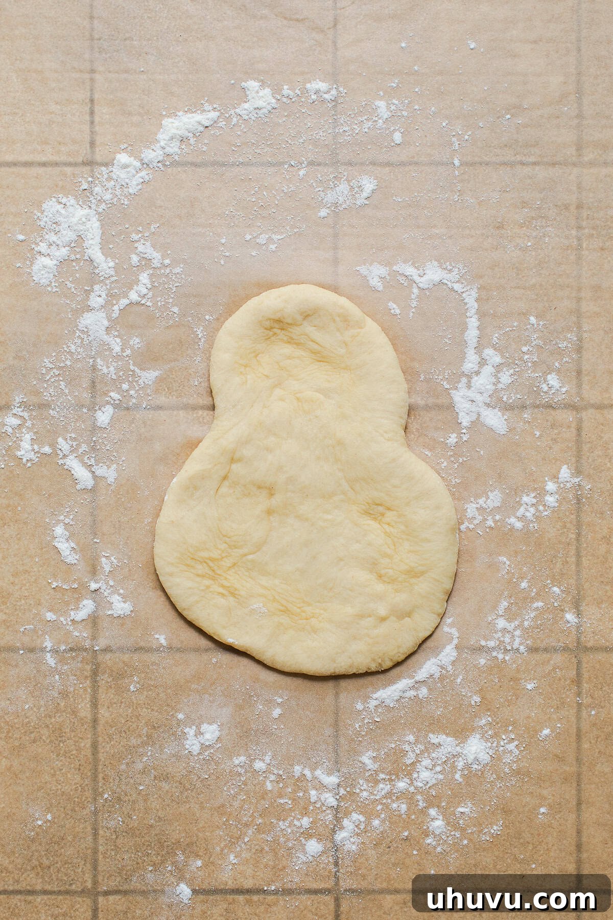 Authentic Cemita Buns: Mexican Sesame Sandwich Rolls 6 Cemita bun dough flattened into a snowman shape on a floured surface.