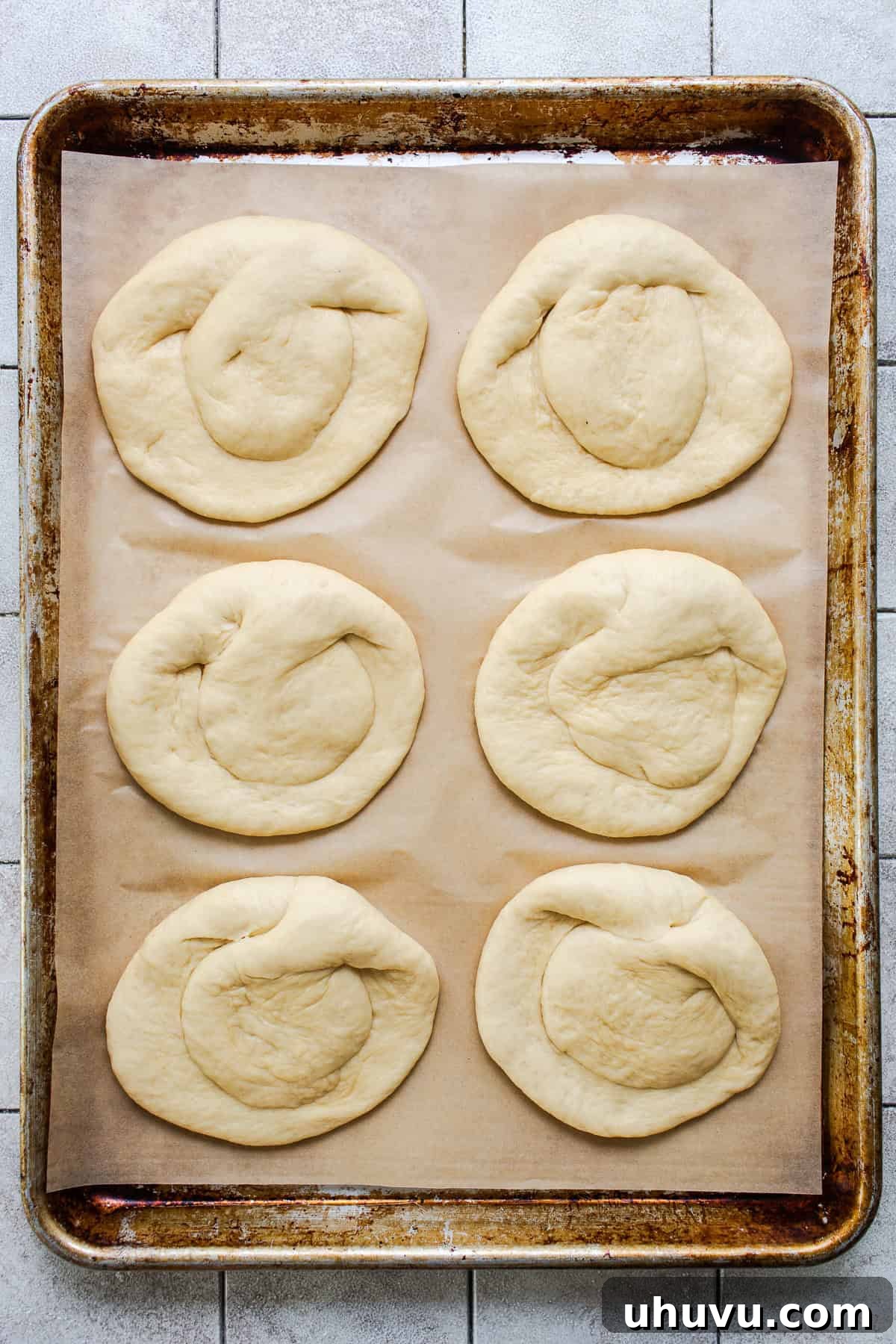 Authentic Cemita Buns: Mexican Sesame Sandwich Rolls 7 Six shaped cemita buns on a parchment-lined baking sheet before rising.